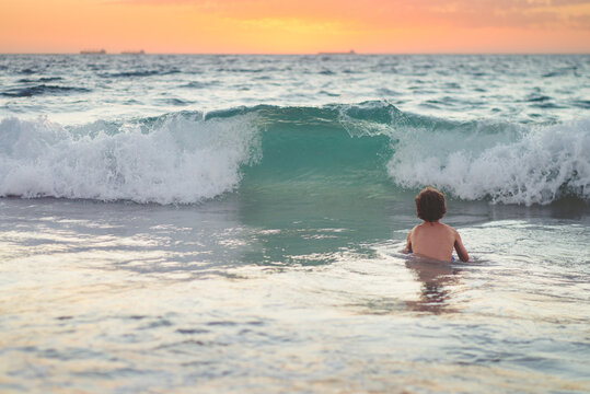 Boy swimming at the beach at sunset