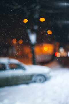 Snow covered sidewalk with parked car. Blurred image.