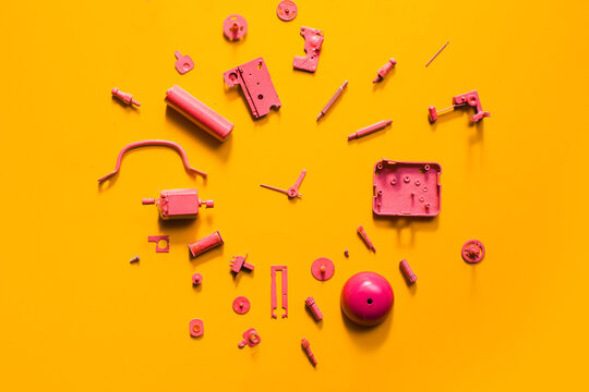 Organised Disassembled Clock/pink parts on orange background