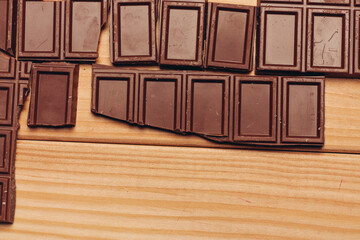 broken bar of chocolate on wooden background top view texture sweets candy