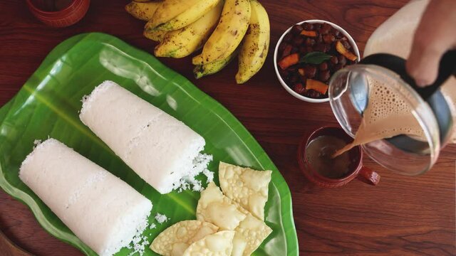 Rice Puttu white Pittu , Kadala Chickpea curry , milk tea , popular South Indian breakfast steamed rice cake 4K slow motion video footage Kerala Tamil Nadu India Sri Lanka. rice flour grated coconut  