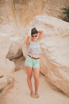Cute girl standing in the sand by rocks