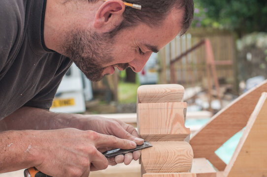 A carpenter carves a piece of wood