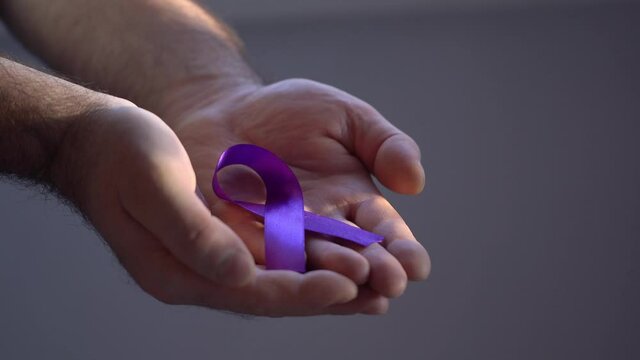 Hands holding purple ribbons, toning copy background, Alzheimer's disease, pancreatic cancer, epilepsy awareness, domestic violence awareness, fibromyalgia awareness, world cancer day