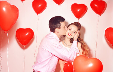 Man with his lovely sweetheart girl kiss at Lover's valentine day. Valentine Couple. Couple kiss and hug. On background red balloons hearts. Love concept