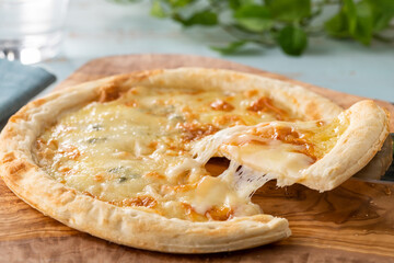 ピザサーバーで持ち上げられた、とろーりチーズのピザ