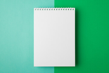 Above flat lay overhead close up view photo of clear notepad with half turquoise and bright green backdrop