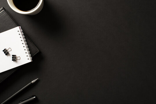 Workplace of tidy professional boss in company concept. Overhead above view photo of leather book spiral copybook pen and a cup of dark beverage isolated black backdrop with empty space