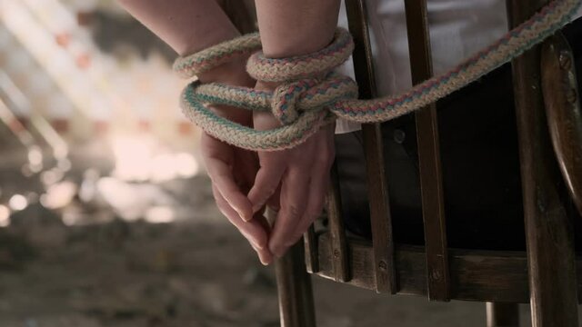Woman's hands tied with rope closeup. kidnapping victim is trying to free his hands from rope.