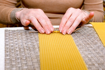 Obraz premium Making a candle from a plate of beeswax. DIY wax candle making process. Step-by-step instruction. Step 3. Twisting. Candle formation.