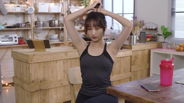 attractive young woman putting up hair into ponytail before going for a run in the morning. background cozy home dining room. healthy lifestyle, real moments