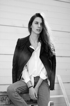 Black and white photo of a girl sitting in fron of white doors
