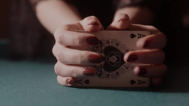 Stylish woman shuffling cards on a green poker table. Luck concept, preparing for a game of poker. Gambling, taking a risk to win.