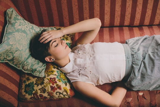 Beautiful girl lying on vintage couch with hand on head