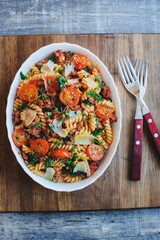 cooking tasty comfort food - italian fusilli pasta baked with meat sauce, cherry tomatoes and cheese
