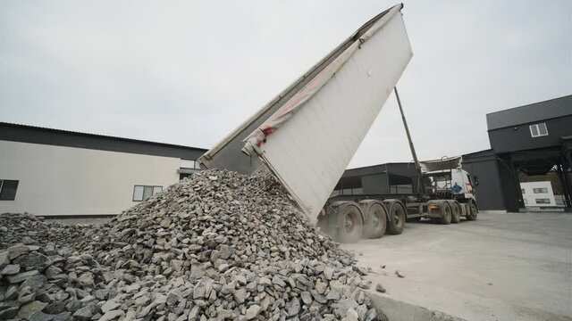 A truck dumps rubble onto a construction site. Clearing site