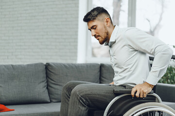 Disabled man tries to sit down on a sofa from wheelchair