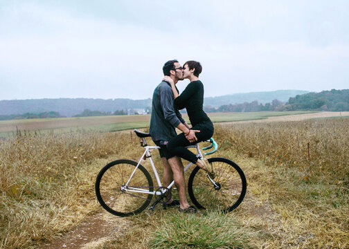 Man kissed woman in the rain as she sits on the handlebars of his bike