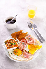 breakfast with fried egg, bacon, toast and bean