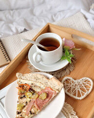 happy spring summer morning concept. A slice of pizza and a cup of tea decorated with a spring flower on the bed. Selective focus