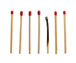 One burnt out match among whole ones on white background