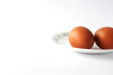 Eggs in a premium plate in half view isolated on white background along with a blank for witing. Ingredients background. Brown Chicken eggs.