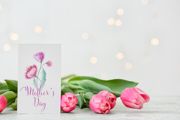Beautiful flowers and greeting card for Mother's Day on light background