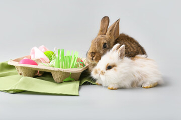 Cute rabbits and Easter eggs on grey background