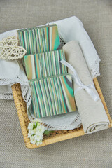 Fototapeta premium Fragrant striped handmade soap in a wicker basket on a white napkin. Personal hygiene items, spa product.