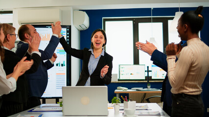 Happy diverse businesspeople designers giving high five during team corporate brainstorm receving good news. Multiethnical partners coworkers celebrate successful teamwork result at company briefing