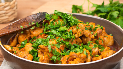Chicken curry sprinkled with chopped parsley in a bowl on a wooden brown table, close up