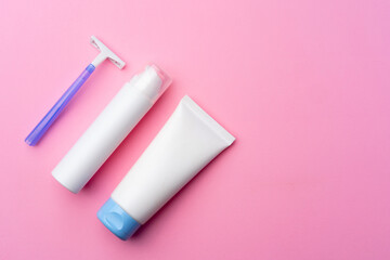 Shaving gel and disposable shaver on pink background top view