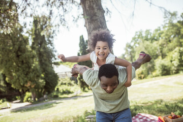 African american dad and his daughter having good time together in the park and feeling cheerful