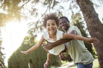 Cute curly kid spending time with her dad in the park