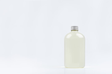 Transparent plastic low thick bottle with pale fresh drink or cosmetic essential oil with silver cap mockup on white background, template, copy space.