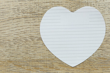 ฺBlank heart of white paper placed on the wooden floor.