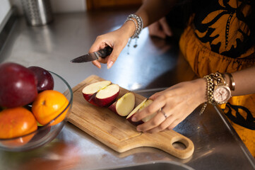 Close-up hands of woman cutting an apple on the wooden board. Cooking, life at home, healthy eating concept