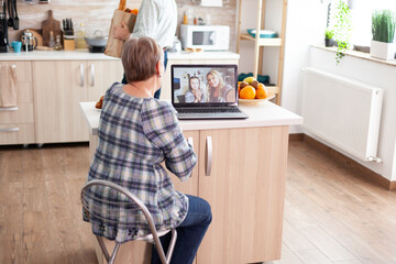 Enthusiastic senior woman talking with family online using laptop webcam during a video conference...