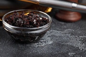 Tobacco for hookah in glass bowl on gray surface