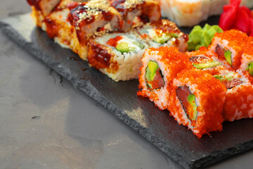 Set of various sushi rolls served on gray background