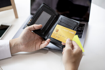 Men are pulling a yellow credit card from their wallet in order to pay for online merchandise...
