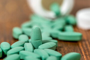 Green medical pills spilling out of a bottle