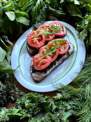 2 vegetarian sandwich on a white plate 
greenery around. Health food. Two slices of bread with curd cheese, chopped herbs, tomatoes and arugula