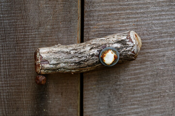 A piece of a branch is used as a lock on a wooden door