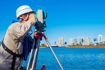 A man with a theodolite on the background of the Rainbow bridge in Tokyo. Construction in Japan....