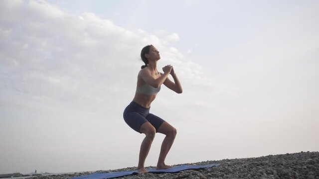 Outdoor fitness. Young woman doing squats 