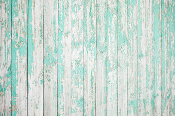 Old wooden fence with light green peeling paint. Part of an old wooden fence. Background of boards with old peeling paint
