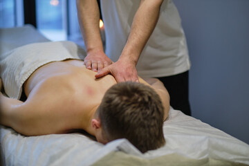 Fototapeta na wymiar Close-up of man enjoying in relaxing back massage . Man relaxing on massage table receiving massage