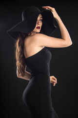fashion portrait of a young and very beautiful girl in a black hat on a black background