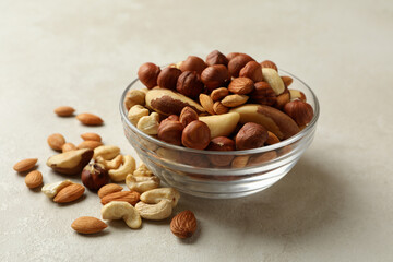 Bowl with different nuts on white textured background